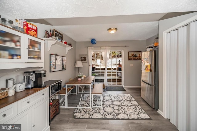 kitchen with white cabinets, dark wood finished floors, dark countertops, glass insert cabinets, and stainless steel appliances