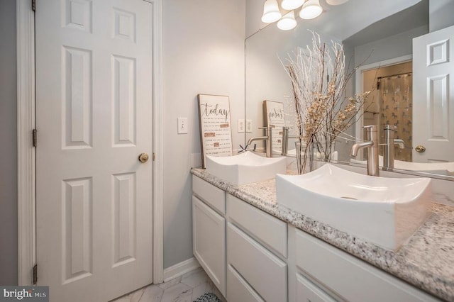 full bathroom with double vanity, marble finish floor, and a sink