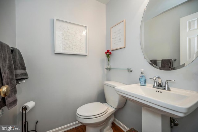 bathroom featuring wood finished floors, a sink, toilet, and baseboards