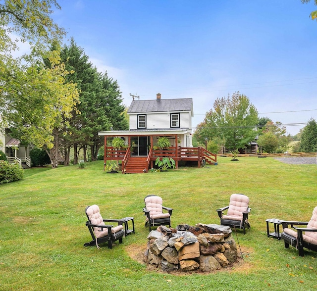 rear view of house with metal roof, an outdoor fire pit, a yard, a wooden deck, and a chimney