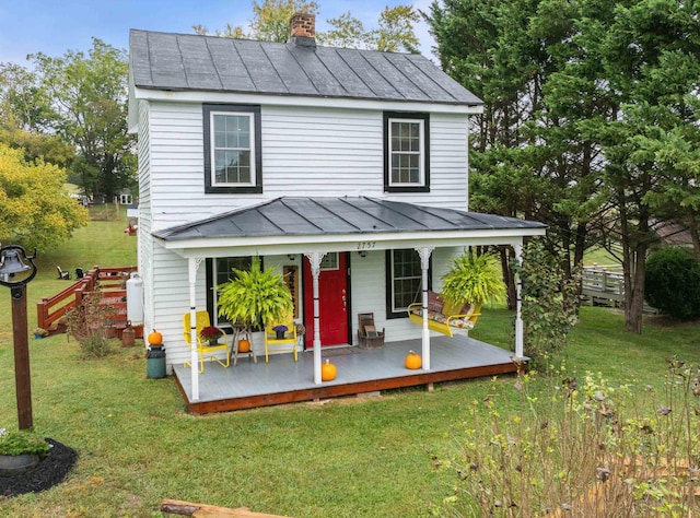 view of front facade featuring a front yard, a standing seam roof, metal roof, and a chimney