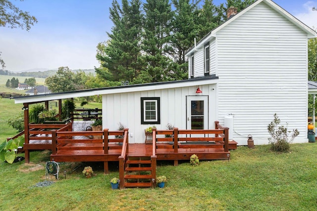 rear view of property with board and batten siding, a lawn, and a wooden deck