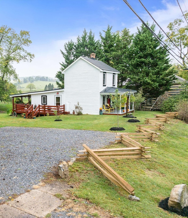 exterior space with a chimney, a lawn, and a wooden deck