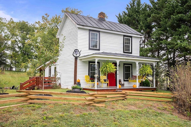 view of front of home with a standing seam roof, covered porch, metal roof, and a chimney