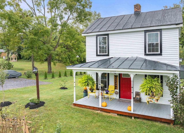 back of property featuring a standing seam roof, a chimney, metal roof, and a yard