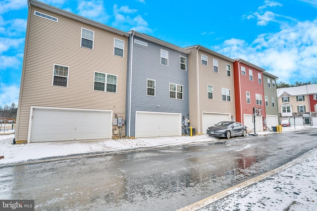 snow covered rear of property featuring a garage