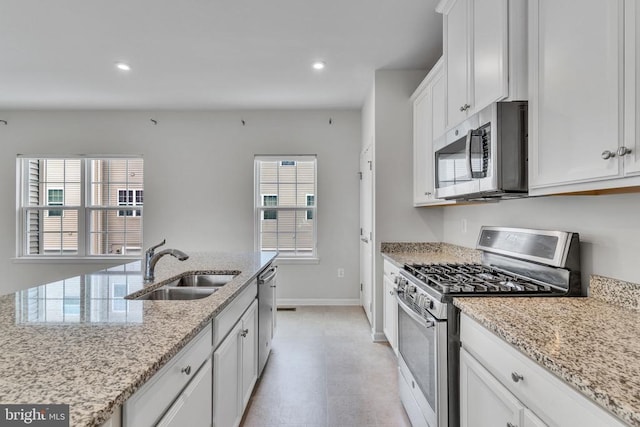 kitchen with light stone counters, recessed lighting, stainless steel appliances, a sink, and white cabinetry