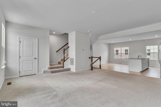 unfurnished living room featuring recessed lighting, visible vents, light carpet, and baseboards