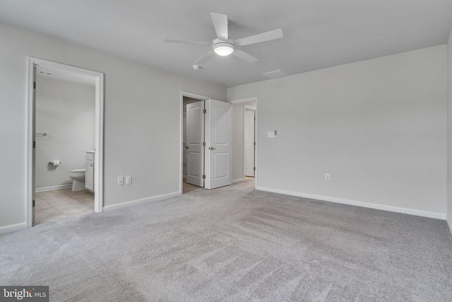 unfurnished bedroom with light carpet, ensuite bathroom, and baseboards