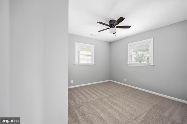 carpeted spare room with ceiling fan, visible vents, and baseboards