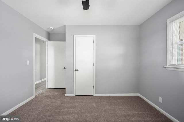 unfurnished bedroom with carpet flooring, a ceiling fan, and baseboards