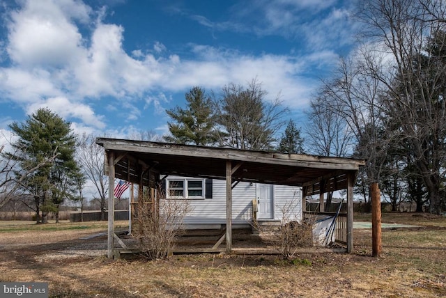 view of outbuilding featuring dirt driveway and a carport