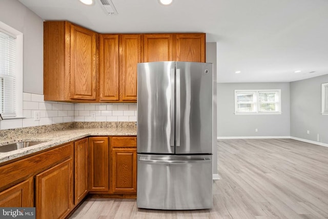 kitchen with brown cabinets, freestanding refrigerator, visible vents, and a sink