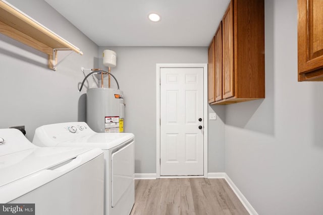 laundry area featuring water heater, cabinet space, light wood-style floors, independent washer and dryer, and baseboards