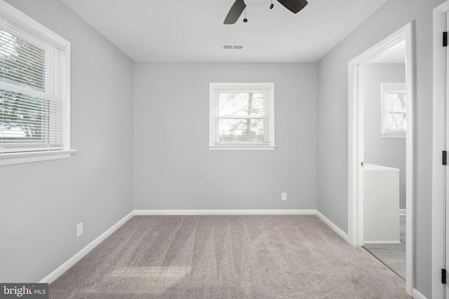 carpeted spare room with a ceiling fan, visible vents, and baseboards