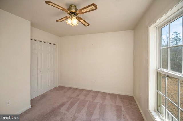 unfurnished bedroom with light colored carpet, a closet, and ceiling fan