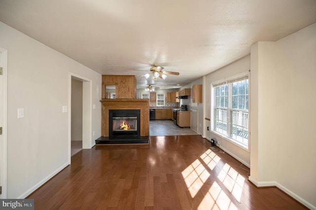 unfurnished living room featuring dark wood-type flooring and ceiling fan