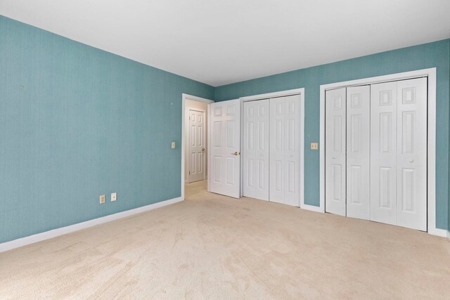 unfurnished bedroom with carpet and two closets