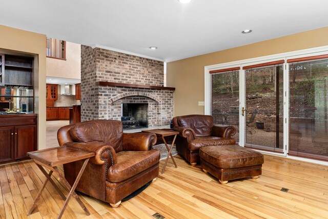 living room featuring a brick fireplace and light wood-type flooring