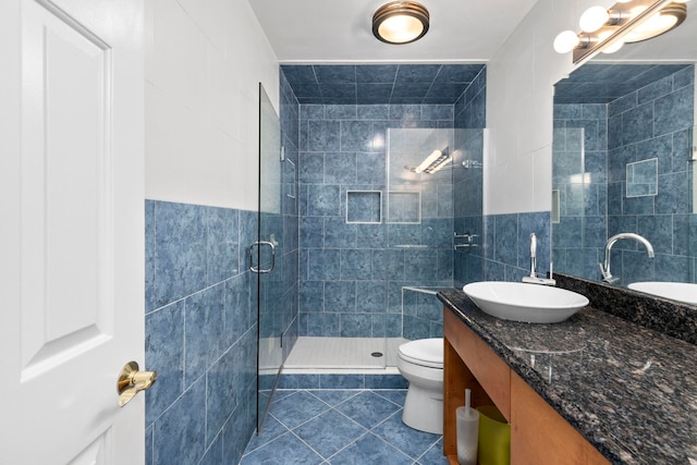 bathroom featuring tile walls, tile patterned flooring, vanity, toilet, and a shower with door