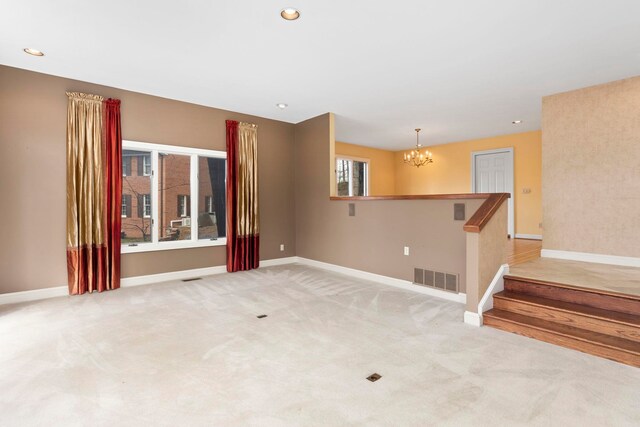 spare room featuring a chandelier and light carpet