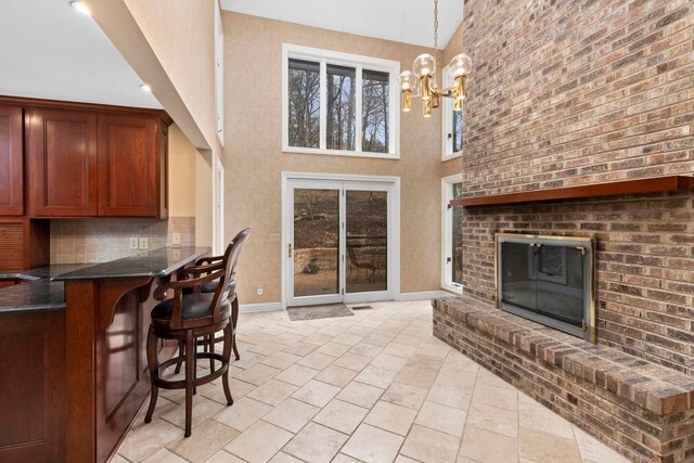 interior space with a brick fireplace, a towering ceiling, and a notable chandelier