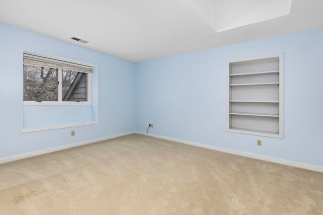 empty room with light colored carpet and built in features