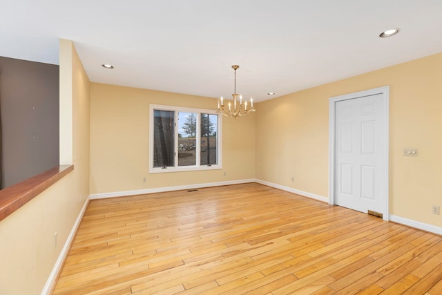 spare room with a chandelier and light hardwood / wood-style flooring