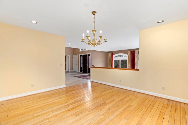 spare room featuring an inviting chandelier and light hardwood / wood-style flooring