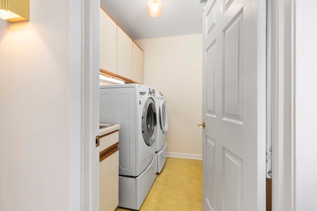 clothes washing area with cabinets and washer and dryer