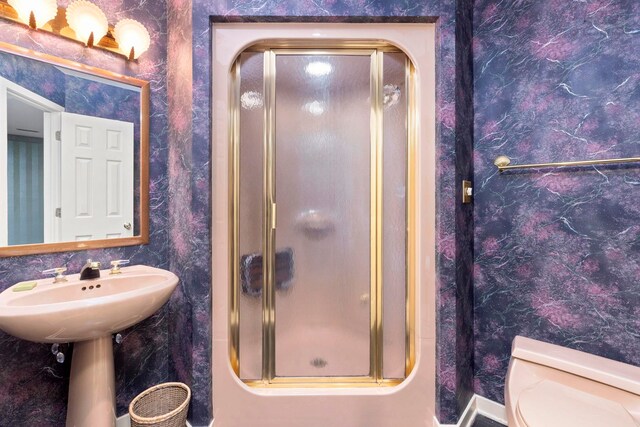 bathroom featuring toilet and a shower with door