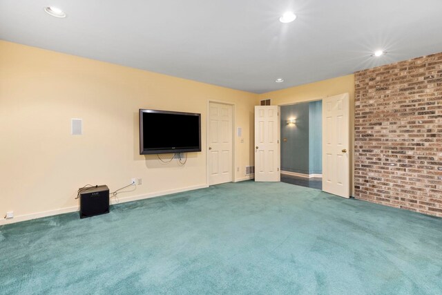 unfurnished living room featuring brick wall and carpet