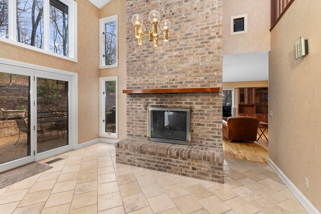 unfurnished living room with a chandelier, a brick fireplace, and a high ceiling