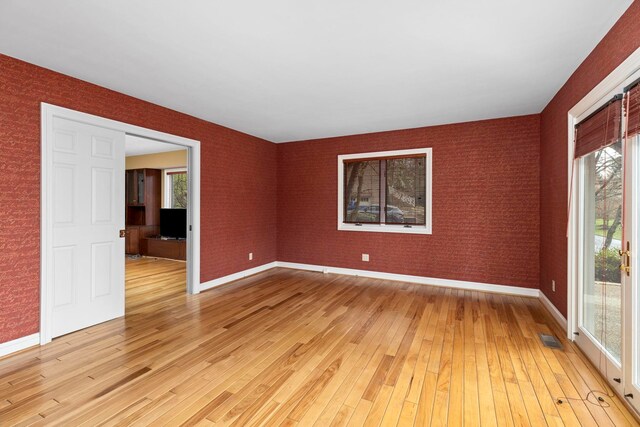 empty room with brick wall and light hardwood / wood-style flooring