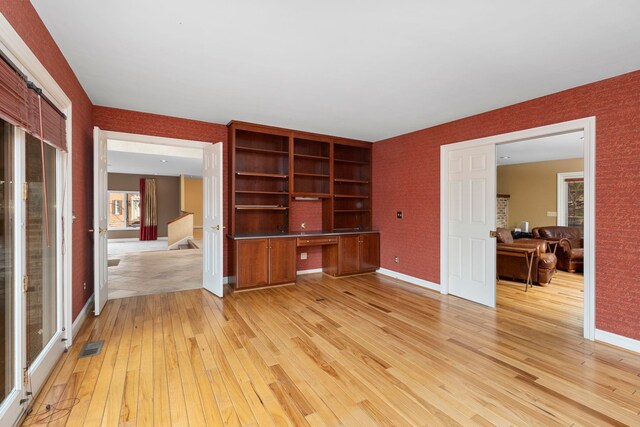 unfurnished living room featuring light hardwood / wood-style flooring and built in desk