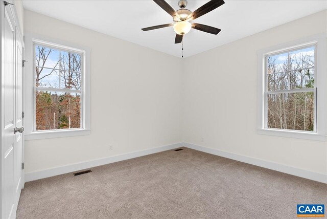 carpeted spare room featuring ceiling fan and plenty of natural light