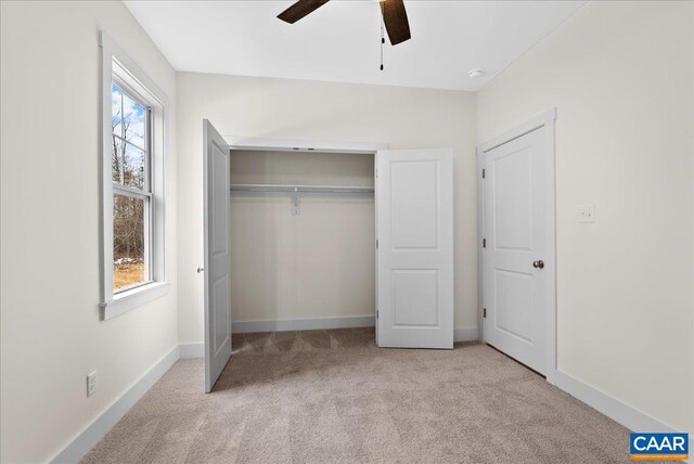 unfurnished bedroom featuring ceiling fan, a closet, and light carpet