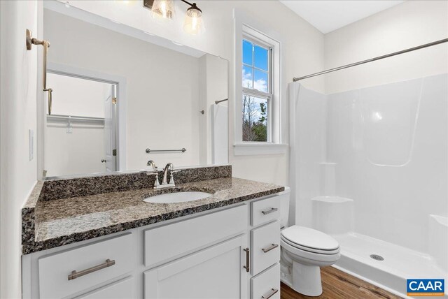 bathroom featuring hardwood / wood-style flooring, vanity, toilet, and walk in shower