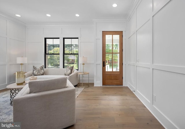 interior space featuring crown molding, light wood-style floors, recessed lighting, and a decorative wall