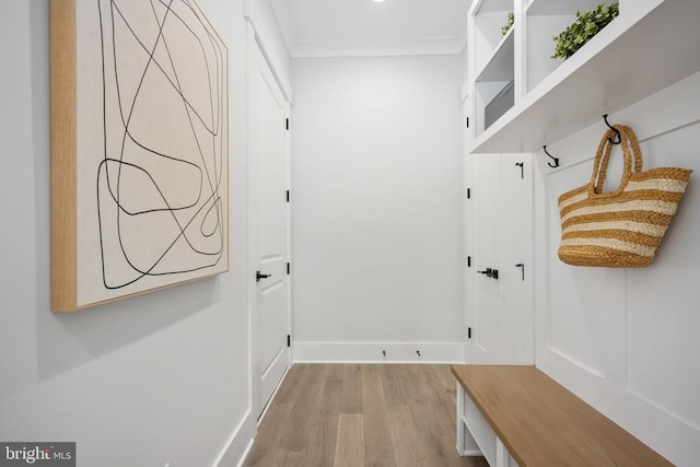 mudroom with light wood-style floors, crown molding, and baseboards