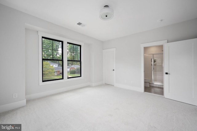 unfurnished bedroom with baseboards, connected bathroom, visible vents, and light colored carpet