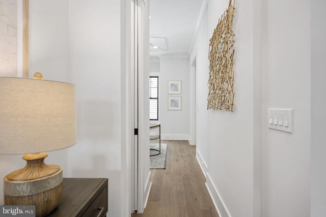 hallway with baseboards, ornamental molding, and wood finished floors