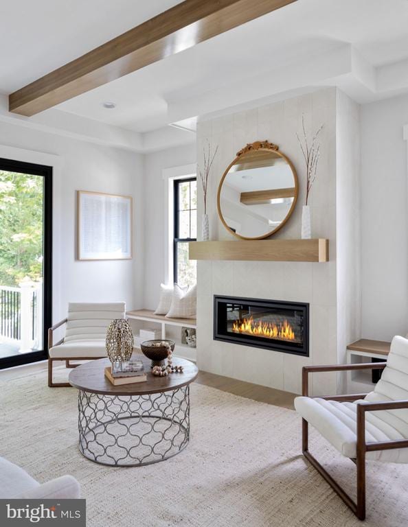 living room featuring beamed ceiling, a fireplace, and wood finished floors