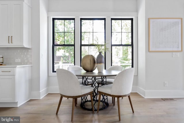 dining area featuring light wood finished floors, visible vents, and baseboards