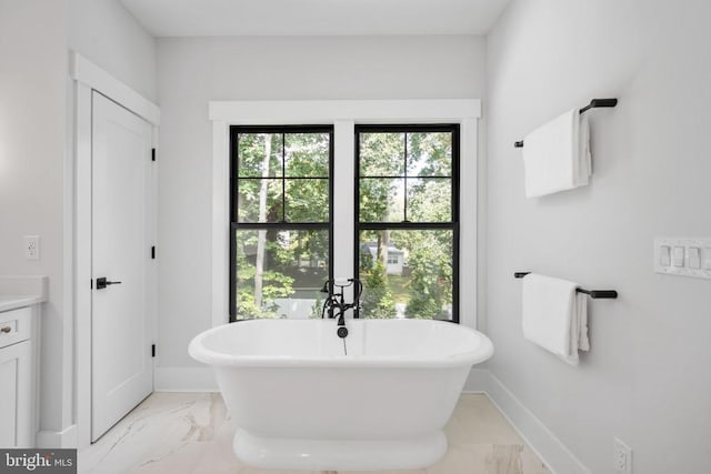 full bathroom featuring a freestanding tub, baseboards, marble finish floor, and vanity