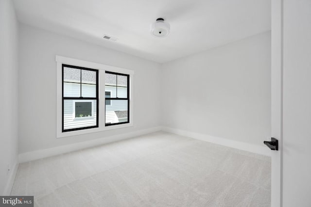 unfurnished room with light carpet, visible vents, and baseboards