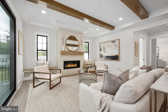 living room with light wood finished floors, beamed ceiling, a fireplace, and a healthy amount of sunlight