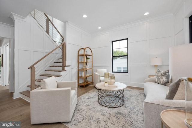 living area featuring ornamental molding, wood finished floors, and a decorative wall