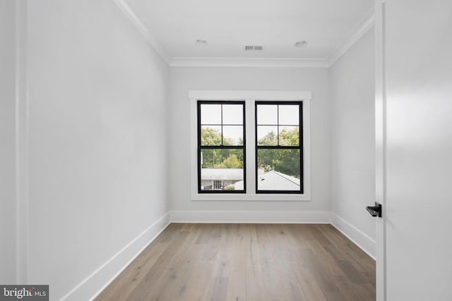 unfurnished room featuring light wood-style floors, visible vents, crown molding, and baseboards