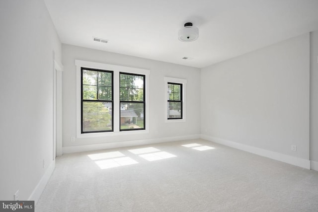 unfurnished room featuring visible vents, baseboards, and light colored carpet